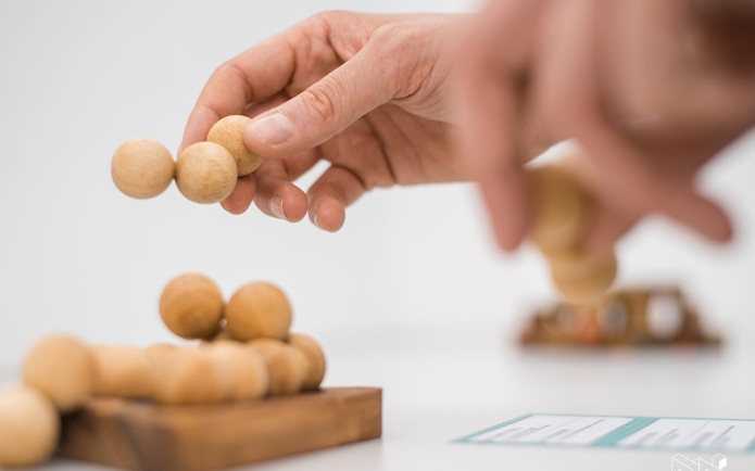Hands interacting with a wooden puzzle at Museum of Illusions Vienna.