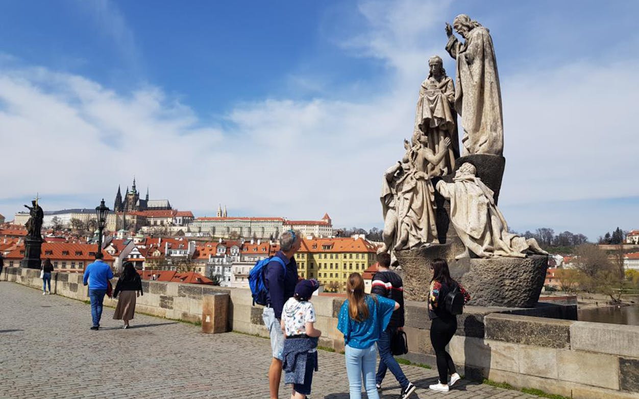 Tourists on Charles Bridge with Prague Castle in the background, part of the Grand Walking Tour.