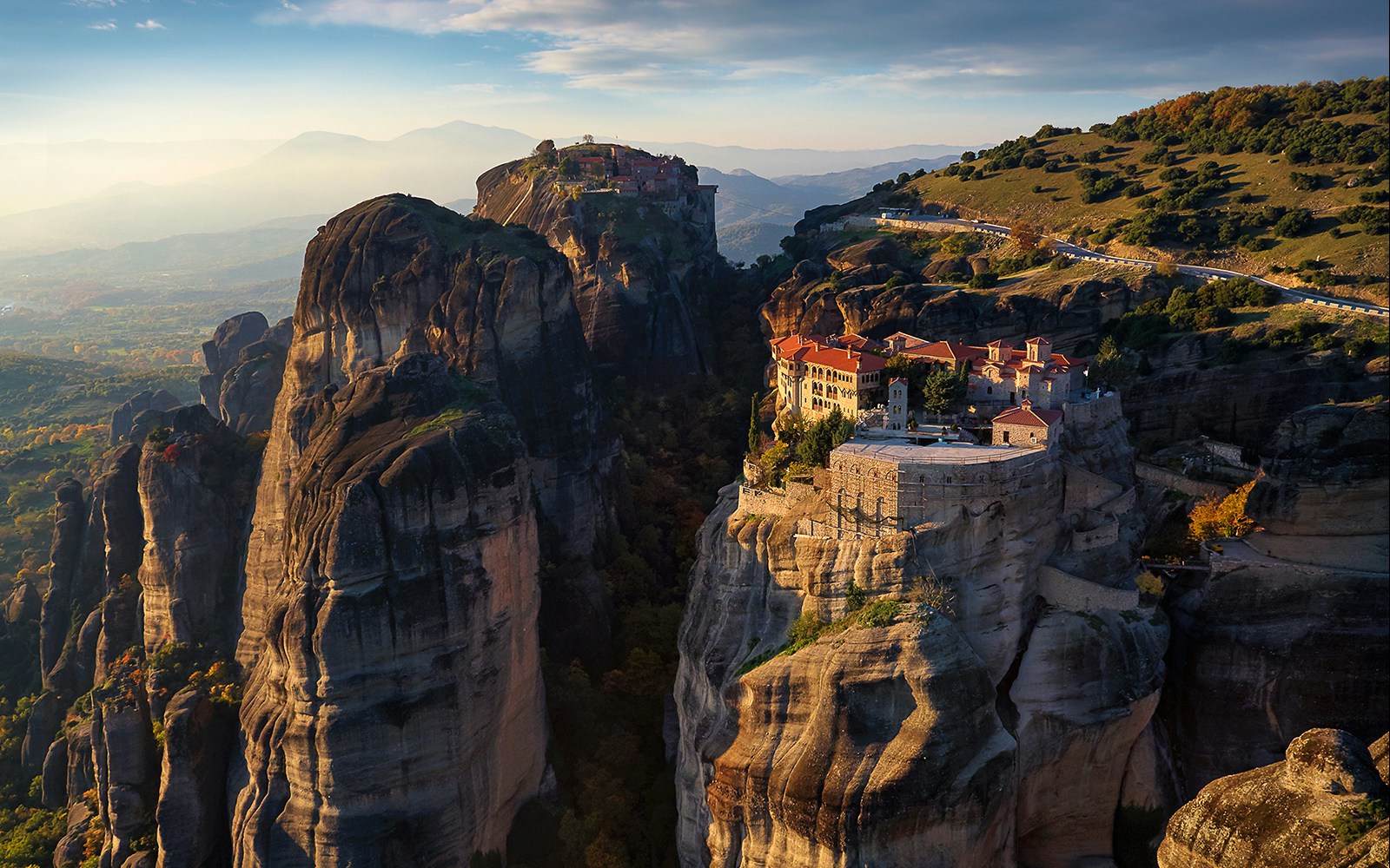 Meteora monasteries perched on rock formations at sunrise, Greece.