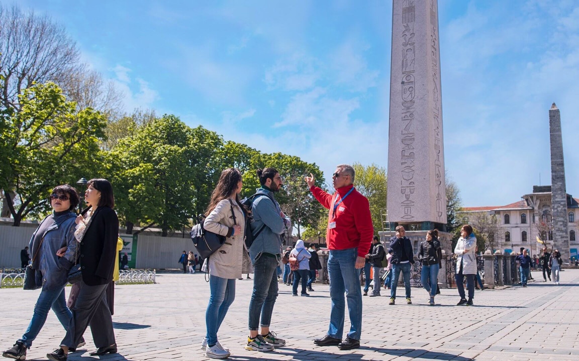 Tour guide explaining the Obelisk of Theodosius in Istanbul's Sultanahmet Square.