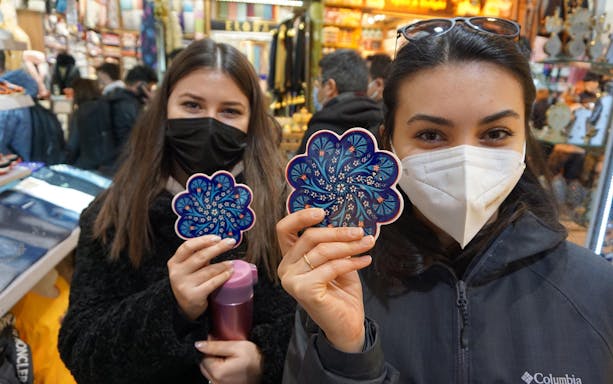 Visitors holding ceramic coasters at Istanbul's Grand Bazaar.