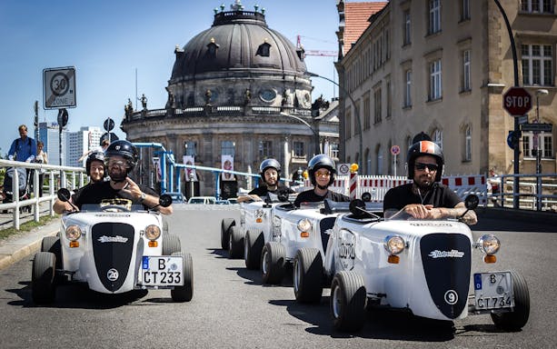 Hot rod cars driving near Bode Museum in Berlin during a city tour.