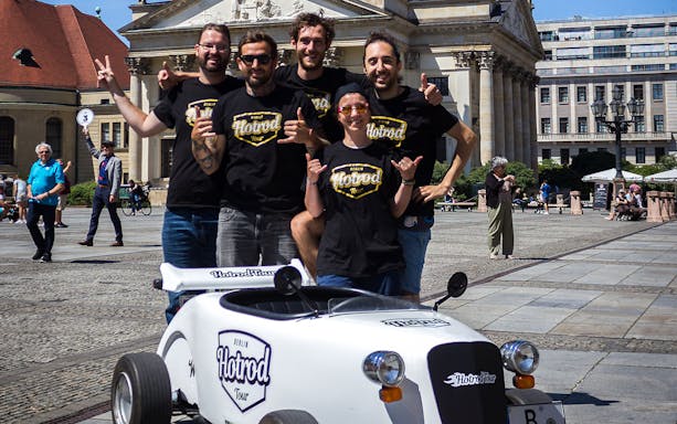 Group posing with hot rod vehicle in Berlin plaza during Hot Rod Tour.