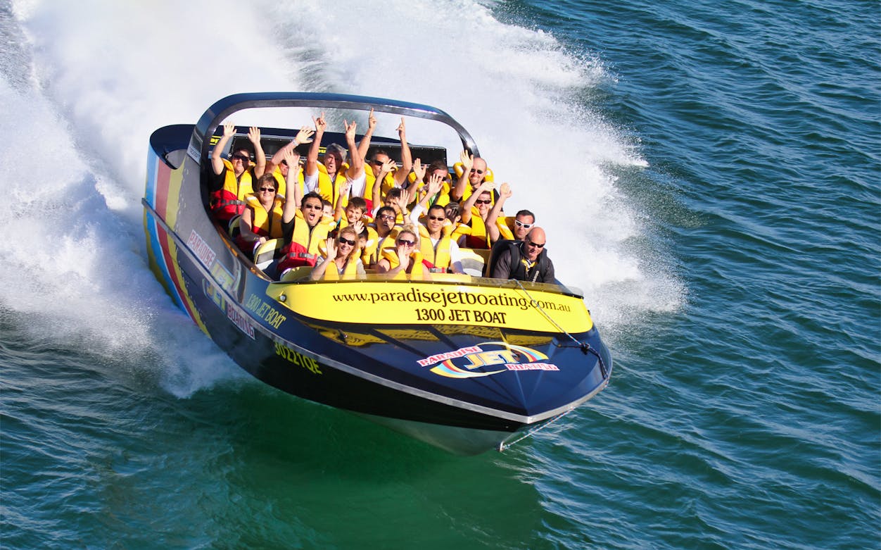 Jetboat speeding on Gold Coast waters with hot air balloon in the sky.