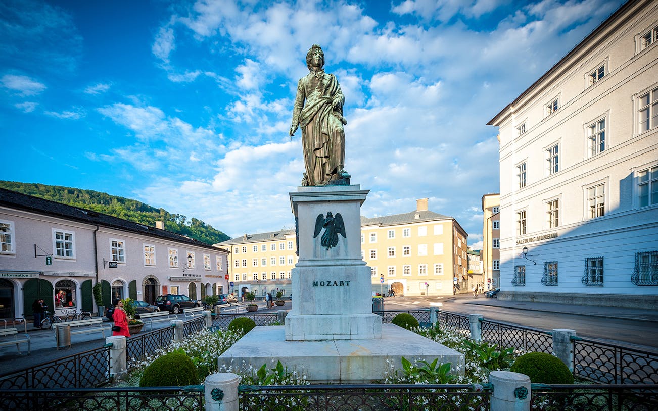 Statue of Mozart in Salzburg city square with surrounding historic buildings.