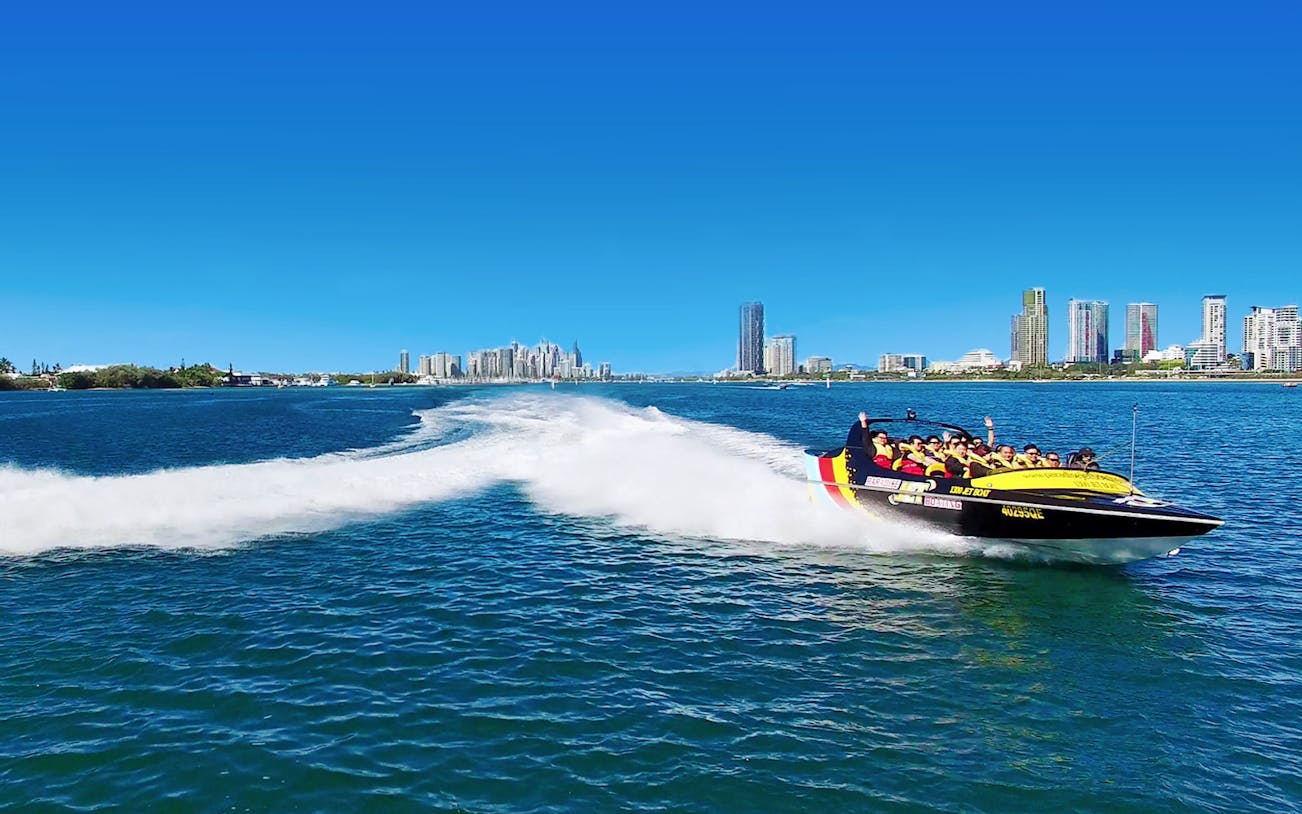 Jetboat speeding on water with city skyline in the background, part of Jetboating & Parasailing Combo for 2.