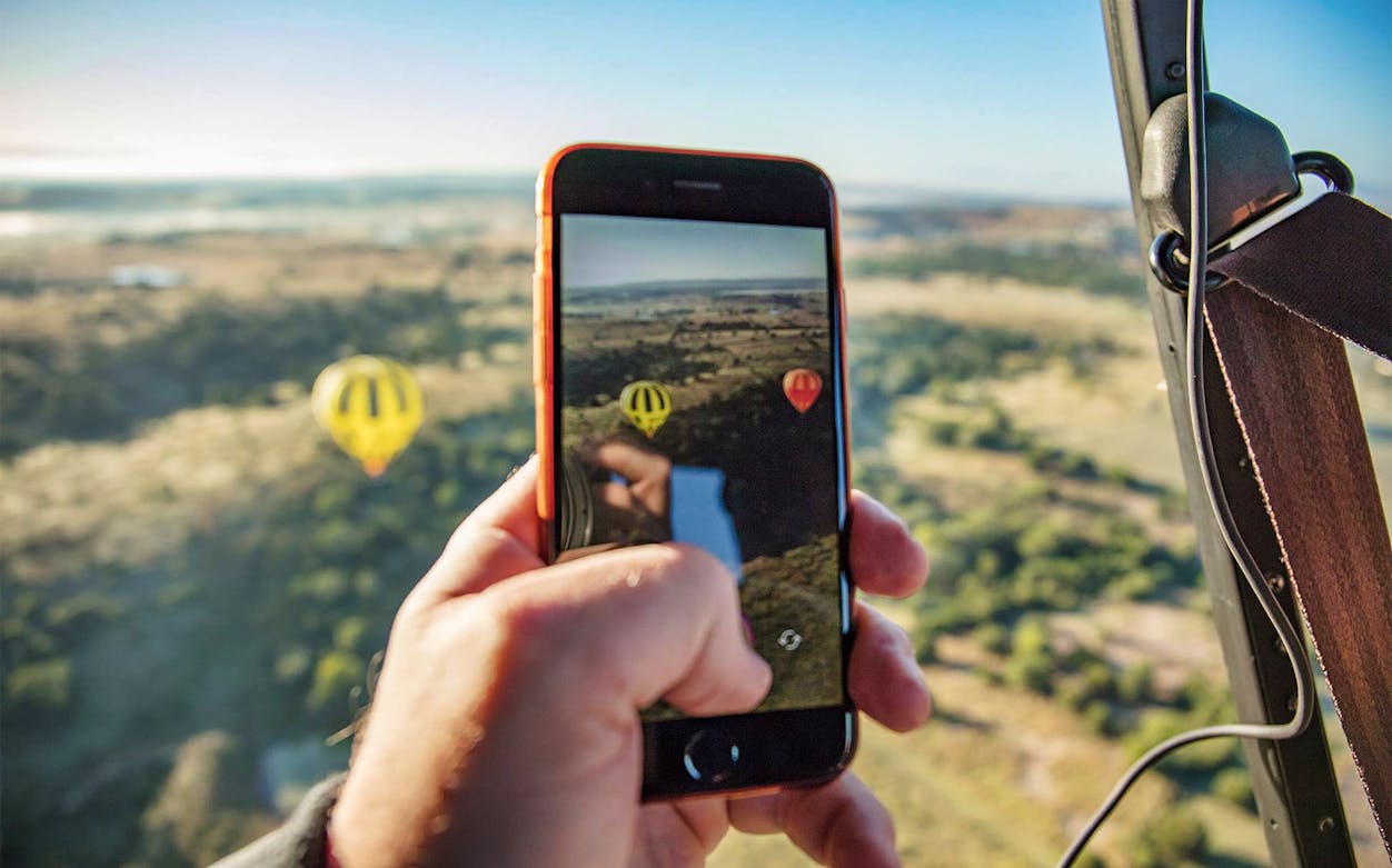 Hot air balloons over Greater Brisbane landscape captured on a smartphone.