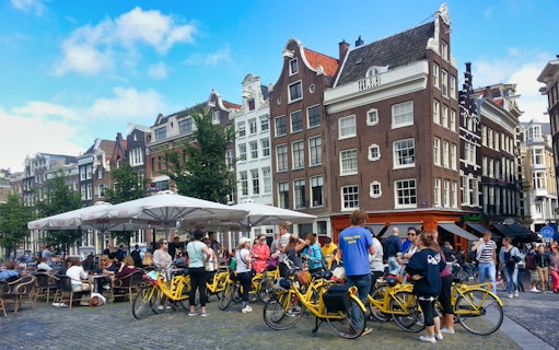 Small group on yellow bikes in Amsterdam's historic district during a guided sightseeing tour.