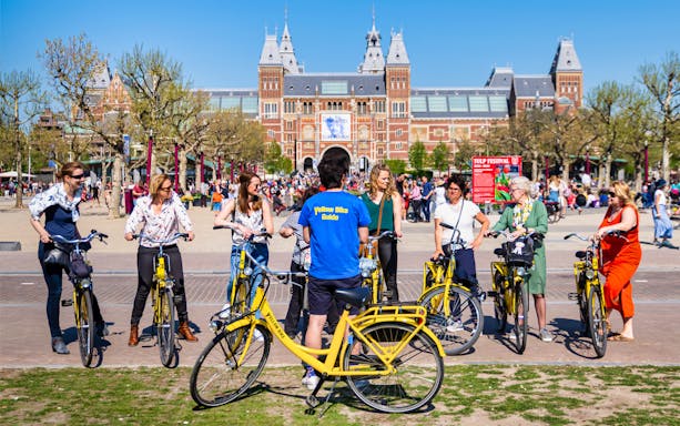 Small group on yellow bikes with guide in front of Rijksmuseum, Amsterdam.