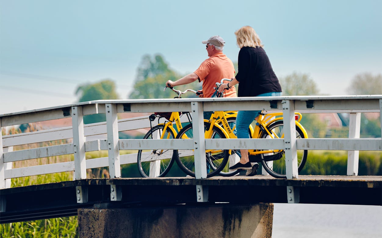 Two people biking on a bridge during a guided tour in Amsterdam.