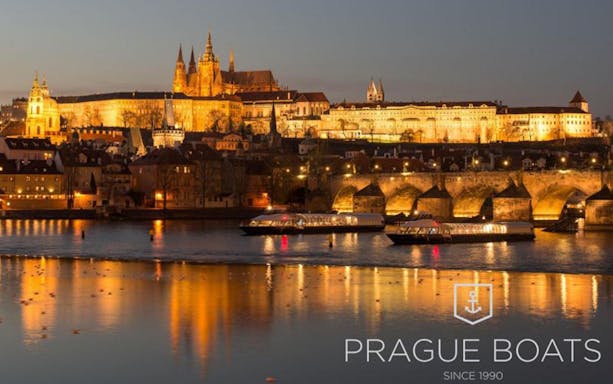 Prague Castle and Charles Bridge illuminated at night during a dinner cruise on the Vltava River.