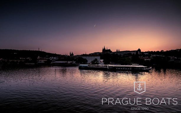 Prague Castle silhouette at sunset during a dinner cruise on the Vltava River.