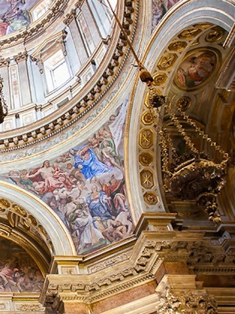 Interior view of the Chapel of San Gennaro's ornate dome with frescoes and chandeliers.