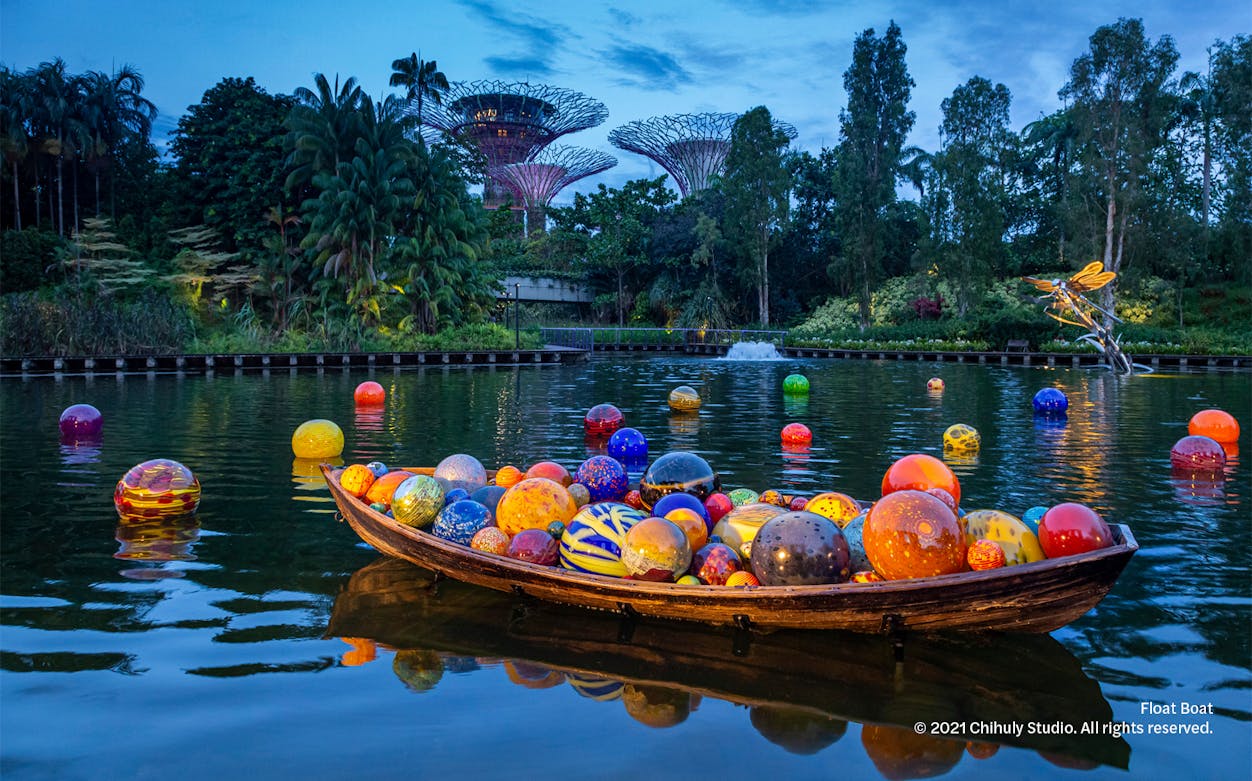 Colorful glass spheres in a boat on water at Gardens by the Bay, part of Dale Chihuly: Glass In Bloom.