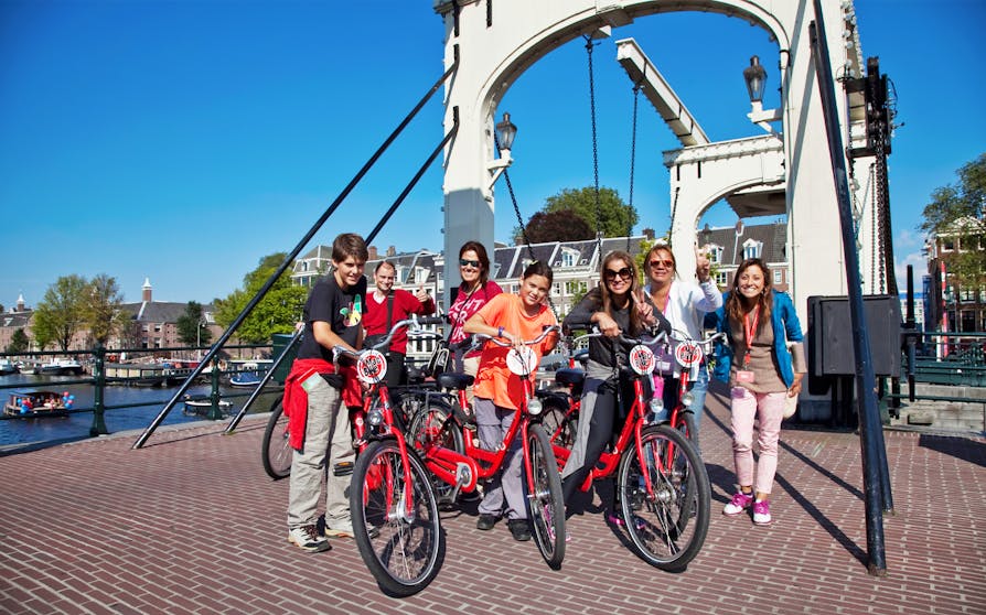 Amsterdam cityscape with cyclist on handbrake bike, highlighting full-day bike rental experience.