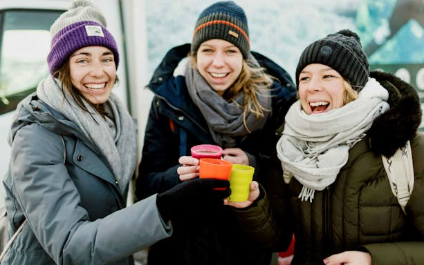 Three people in winter clothing enjoying drinks after snorkeling in Silfra, Iceland.
