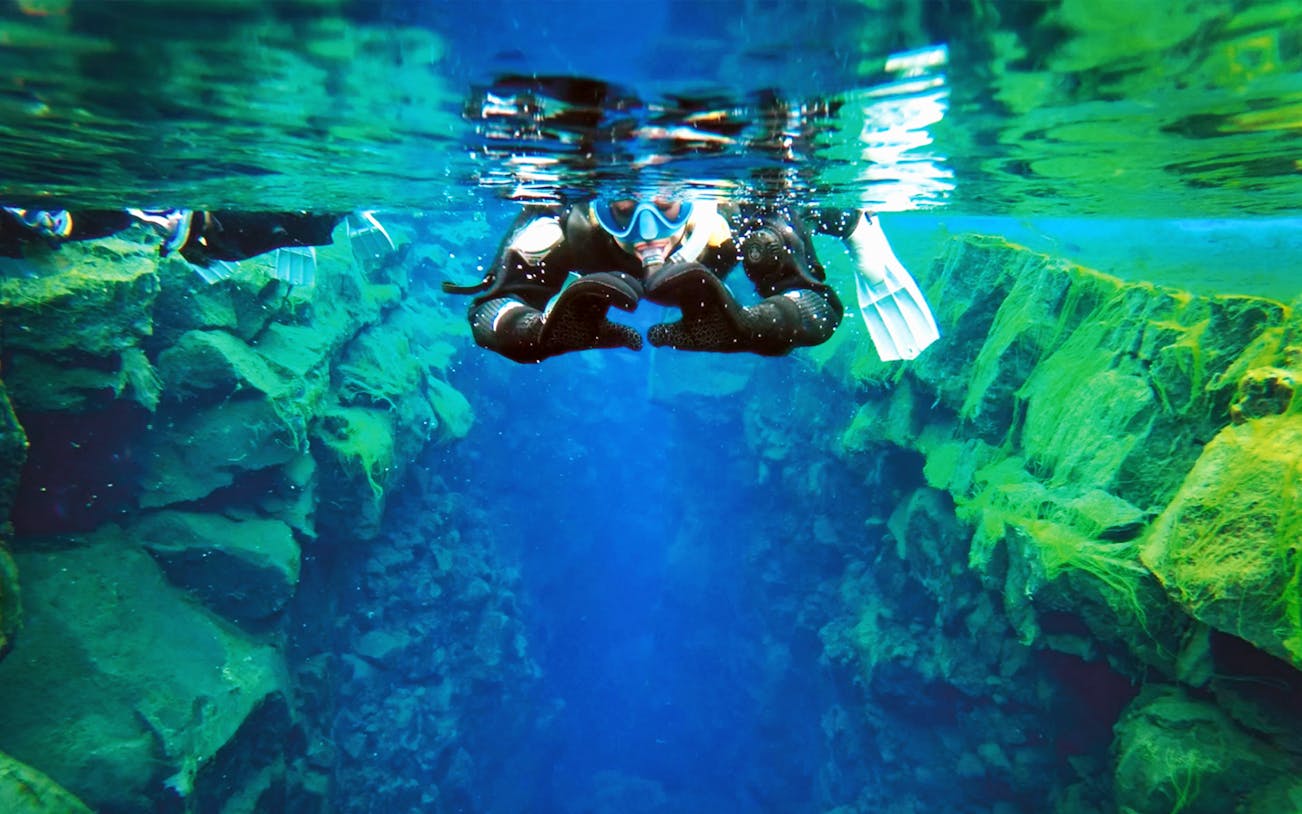 Snorkeler exploring Silfra fissure between tectonic plates in Iceland.