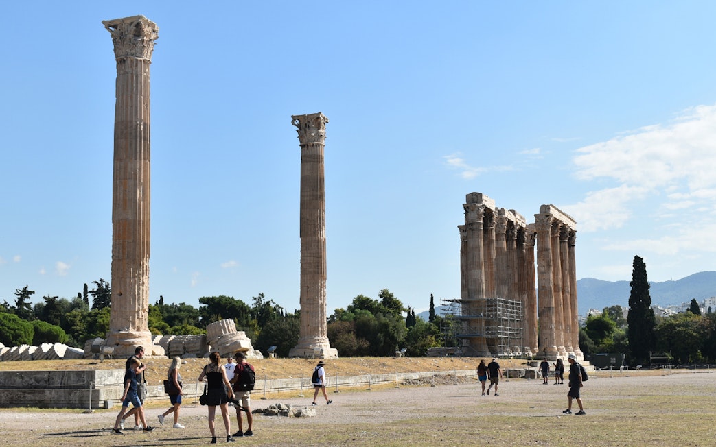 Temple of Olympian Zeus ruins with tourists exploring the site in Athens.