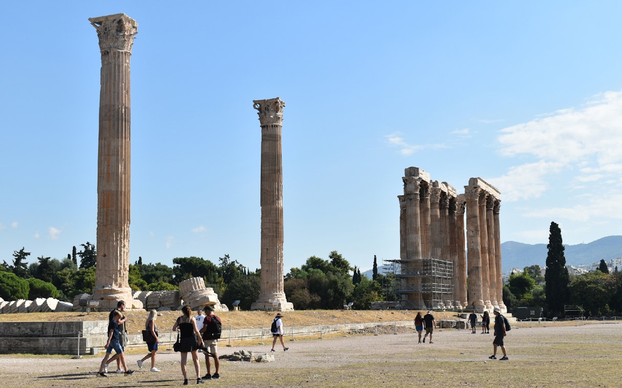 Temple of Olympian Zeus ruins with tourists exploring the site in Athens.