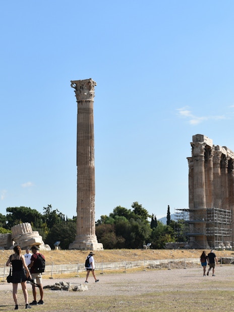 Temple of Olympian Zeus ruins with tourists exploring the site in Athens.