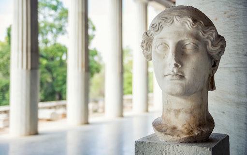 Bust of a classical statue in the Ancient Agora, Athens, with columns in the background.