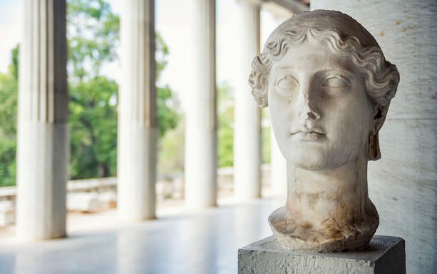 Bust of a classical statue in the Ancient Agora, Athens, with columns in the background.