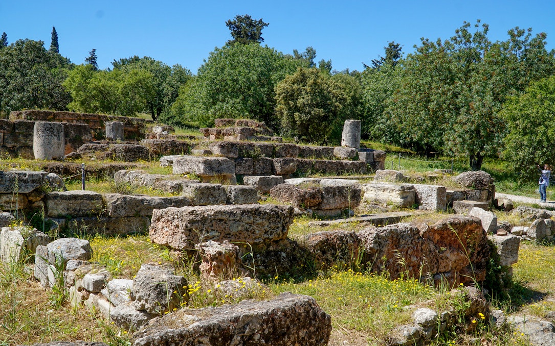 Ancient Agora ruins with stone foundations and greenery in Athens, Greece.