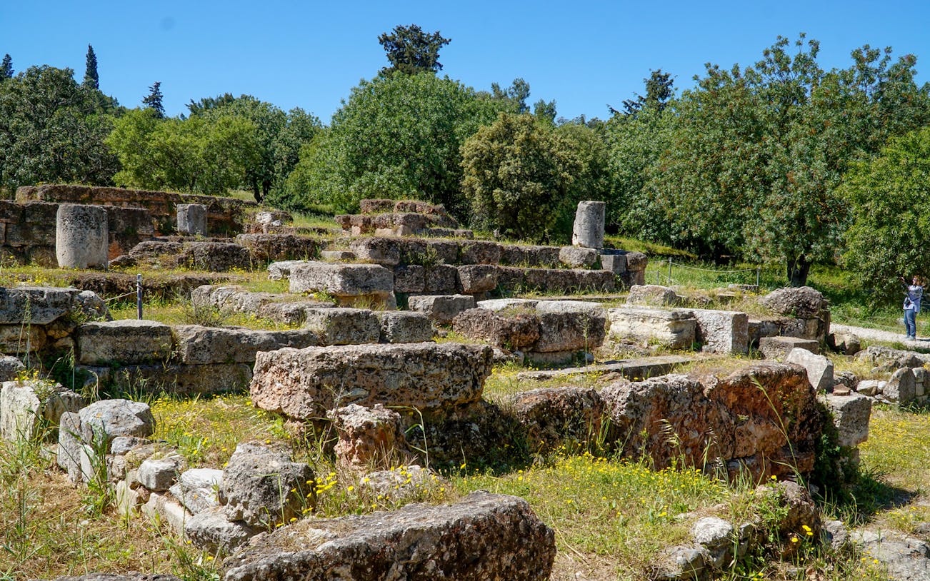 Ancient Agora ruins with stone foundations and greenery in Athens, Greece.