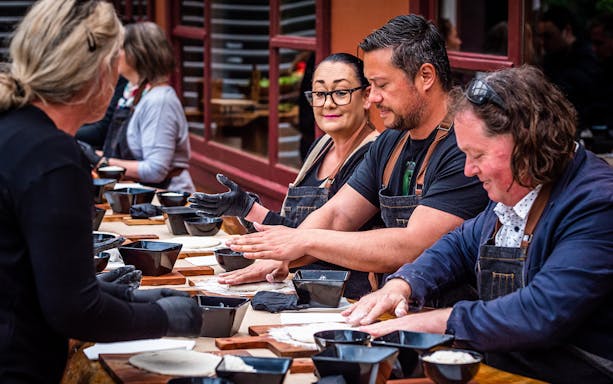 Participants preparing traditional food at Tamaki Maori Village experience.