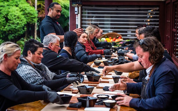 Visitors participating in a traditional cooking class at Tamaki Maori Village, New Zealand.