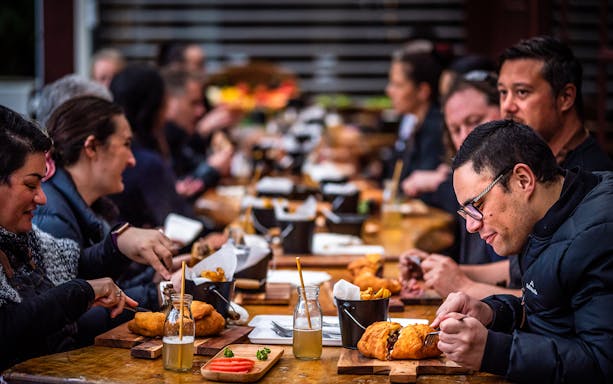 Guests enjoying traditional Maori meal at Tamaki Maori Village dining table.