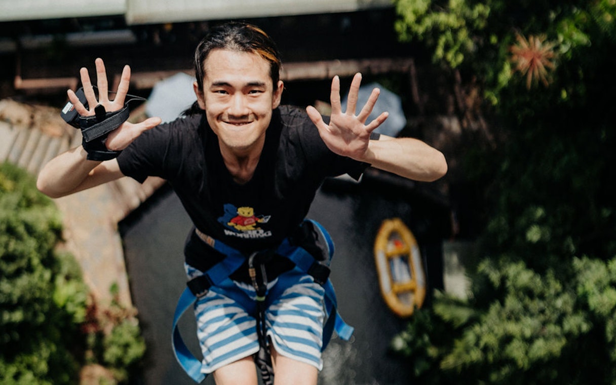 Person mid-air during a bungy jump in Cairns, Australia, with lush greenery below.