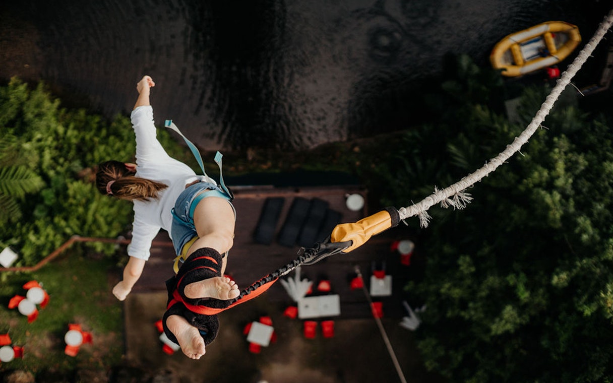 Person bungy jumping over lush greenery in Cairns, Australia.