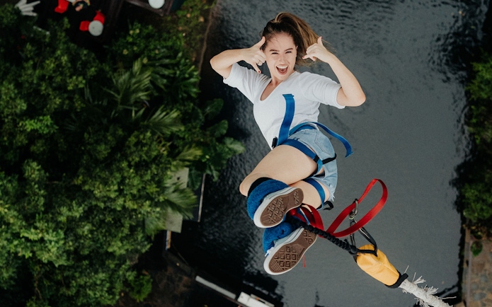 Person bungy jumping over lush greenery and water in Cairns, Australia.