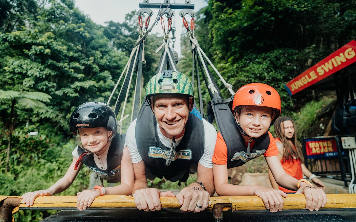 Participants on Cairns Giant Swing in harnesses, surrounded by lush greenery.