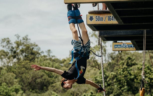 Bungy jumper mid-air at AJ Hackett Cairns platform, Australia.