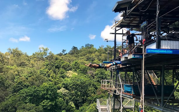 Person bungee jumping from platform at Skypark Cairns, surrounded by lush forest.