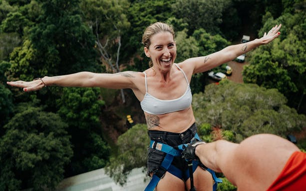 Person bungee jumping at Skypark Cairns, surrounded by lush forest.