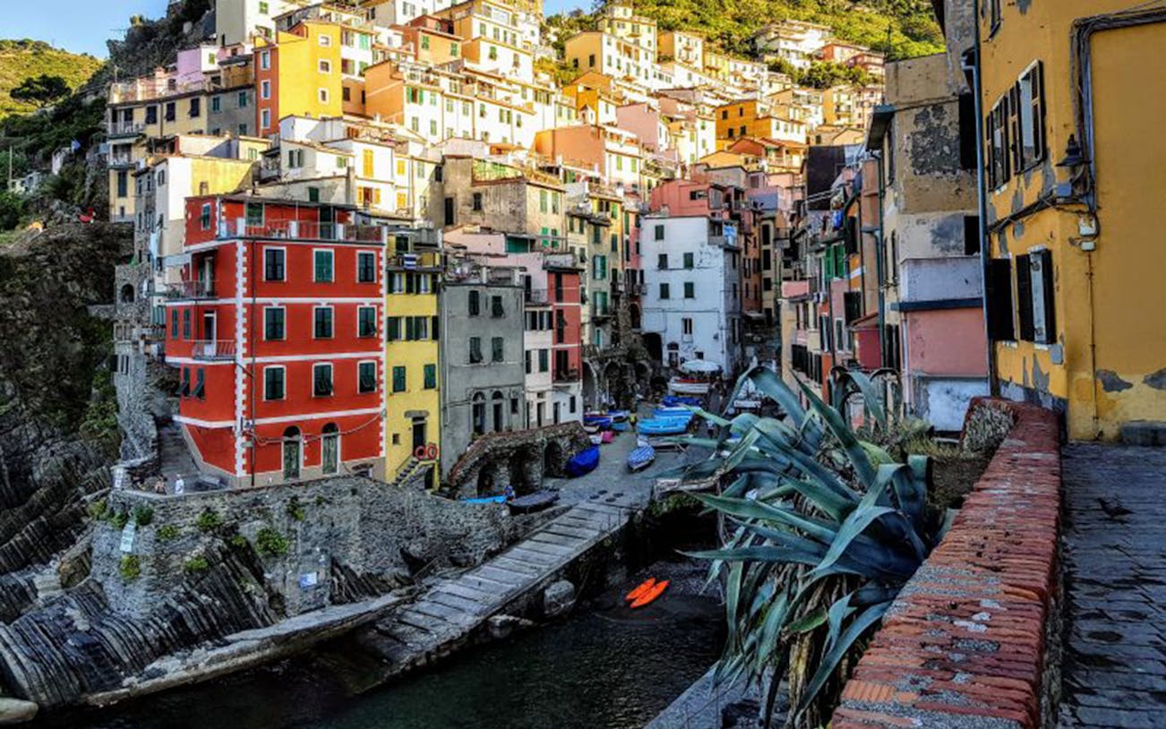 Colorful buildings in Riomaggiore, Cinque Terre, with boats docked along the waterfront.