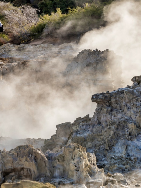 Couple standing amidst geothermal steam at Hell's Gate, New Zealand.