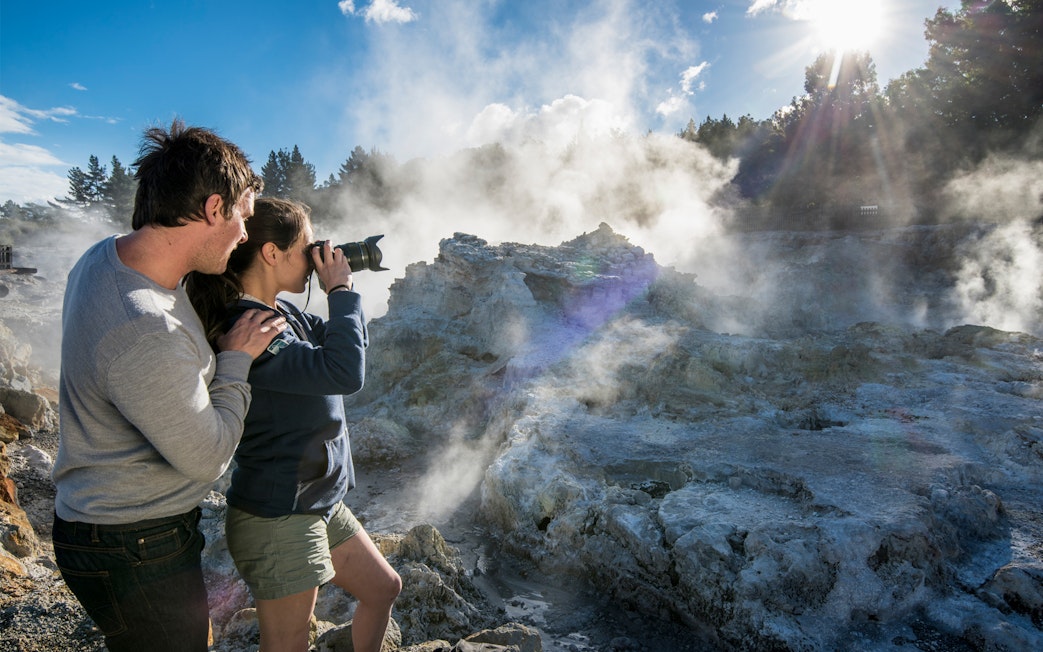 Visitors photographing geothermal steam at Hell's Gate, New Zealand.