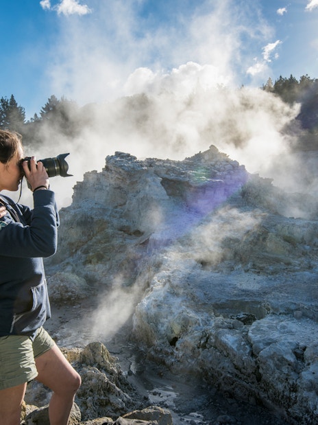 Visitors photographing geothermal steam at Hell's Gate, New Zealand.