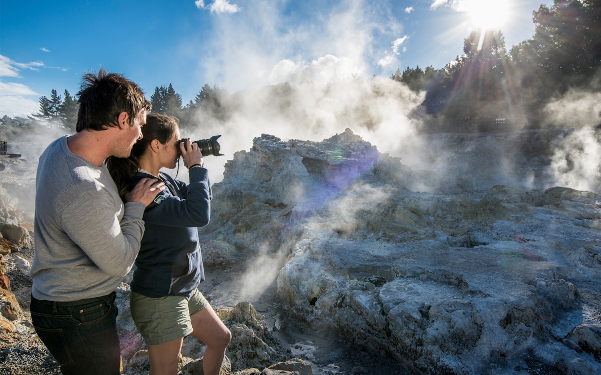 Visitors photographing geothermal steam at Hell's Gate, New Zealand.