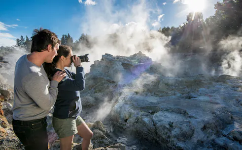 Visitors photographing geothermal steam at Hell's Gate, New Zealand.