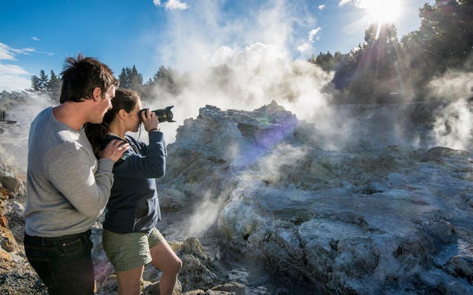 Visitors photographing geothermal steam at Hell's Gate, New Zealand.