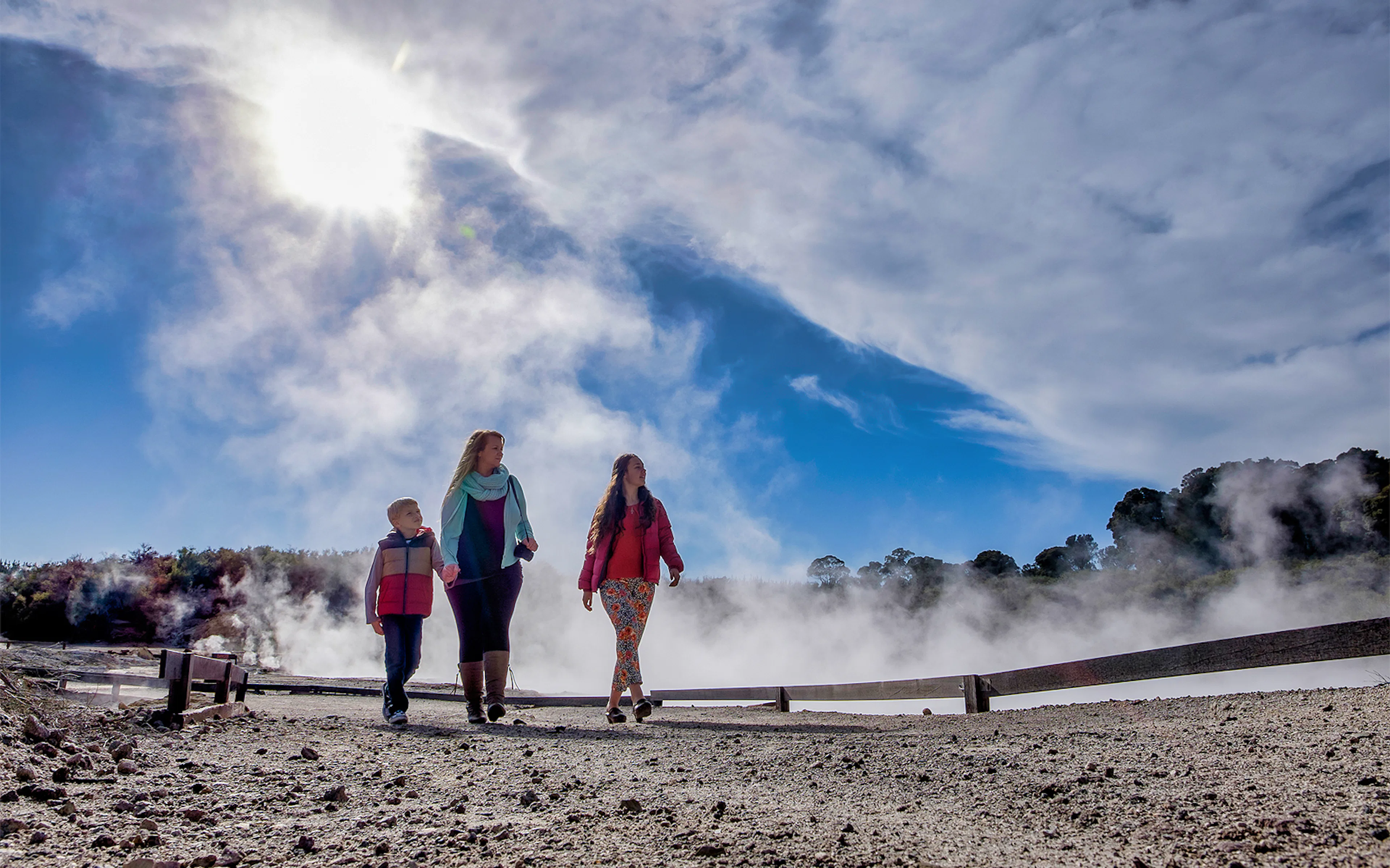 Visitors walking through geothermal steam at Hell's Gate, New Zealand.