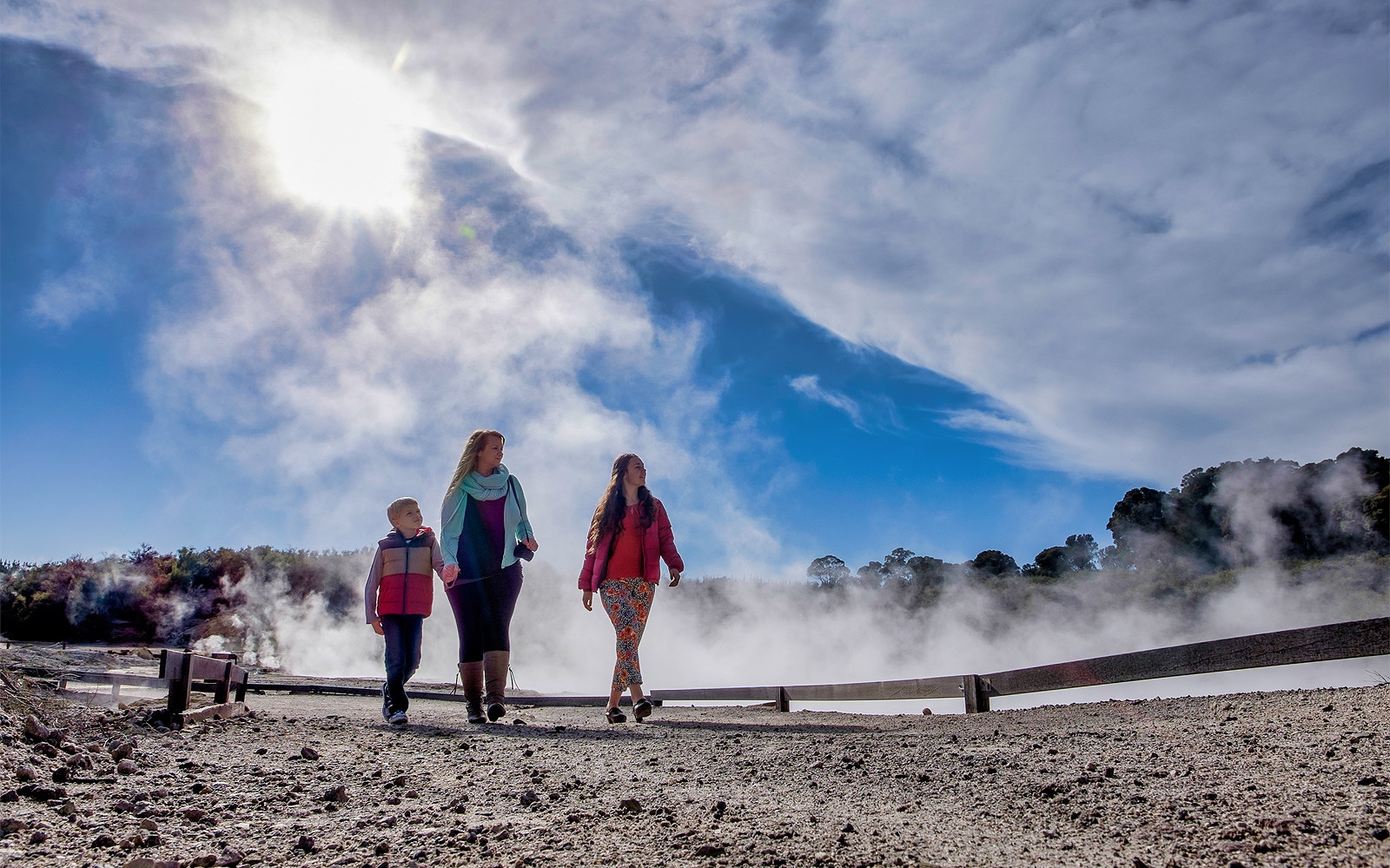 Visitors walking through geothermal steam at Hell's Gate, New Zealand.