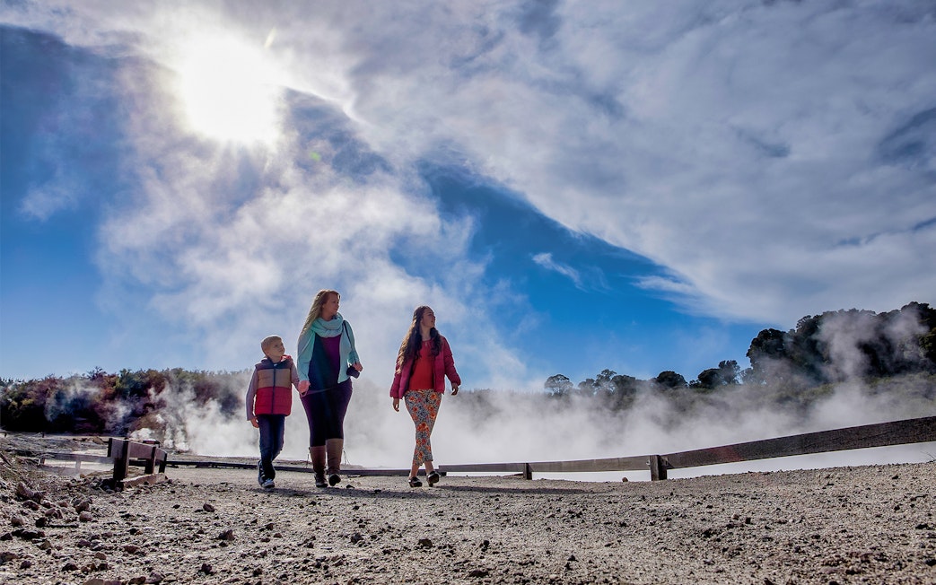 Visitors walking through geothermal steam at Hell's Gate, New Zealand.