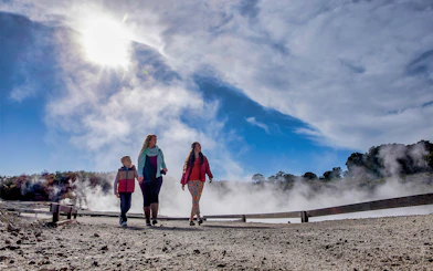 Visitors walking through geothermal steam at Hell's Gate, New Zealand.