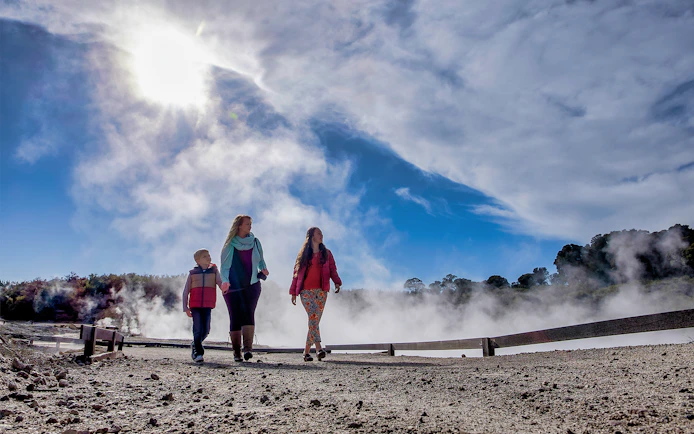 Visitors walking through geothermal steam at Hell's Gate, New Zealand.